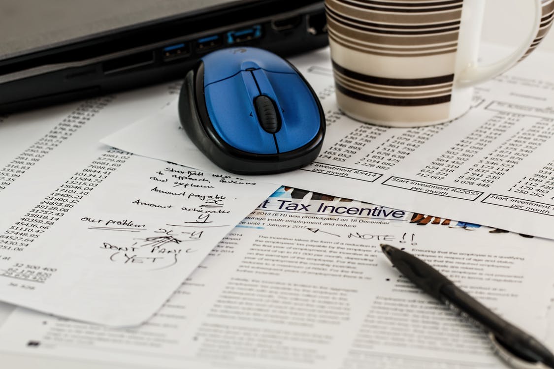 mouse and coffee mug on top papers